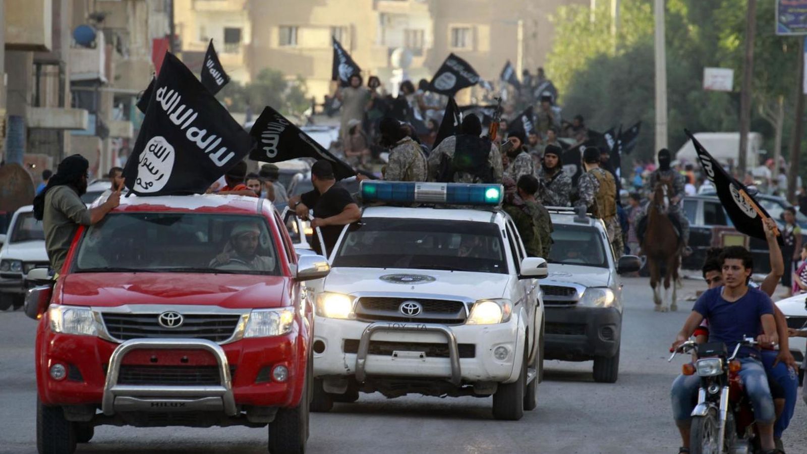 Foto: Militantes del ISIS ondean banderas del grupo durante un desfile militar en Raqqa, Siria (Reuters).