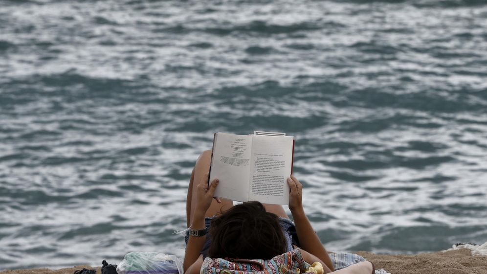 Foto: Una joven disfruta de la lectura de un libro en la playa de la Barceloneta. (EFE)