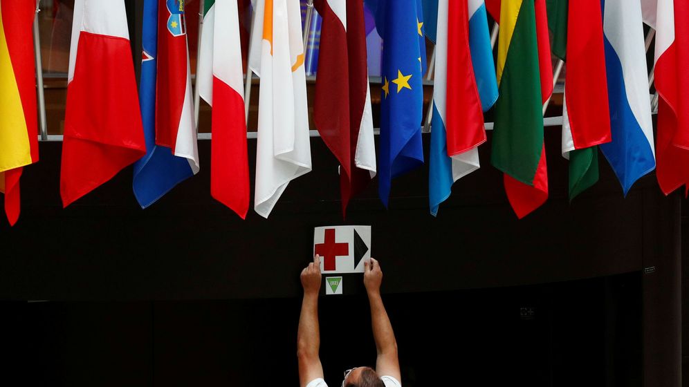 Foto: Un empleado coloca una señal bajo las banderas europeas en el Consejo. (Reuters)