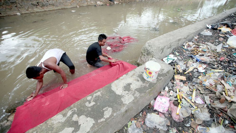 Foto: Unos hombres limpian una alfombra en un rÃ­o contaminado de Indonesia. (EFE)