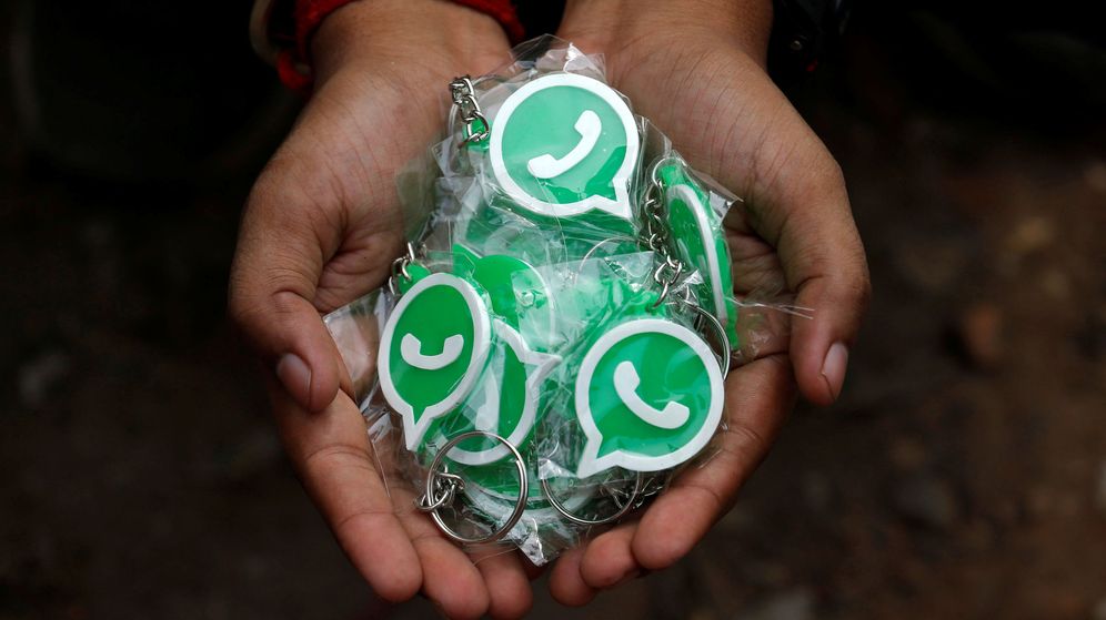 Foto: Una persona sostiene llaveros con el sÃ­mbolo de WhatsApp. (Reuters)