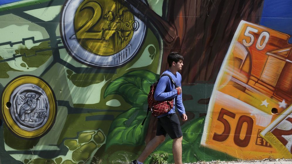 Foto: Un joven pasa junto a una pintada de billetes y monedas de euro. (EFE)