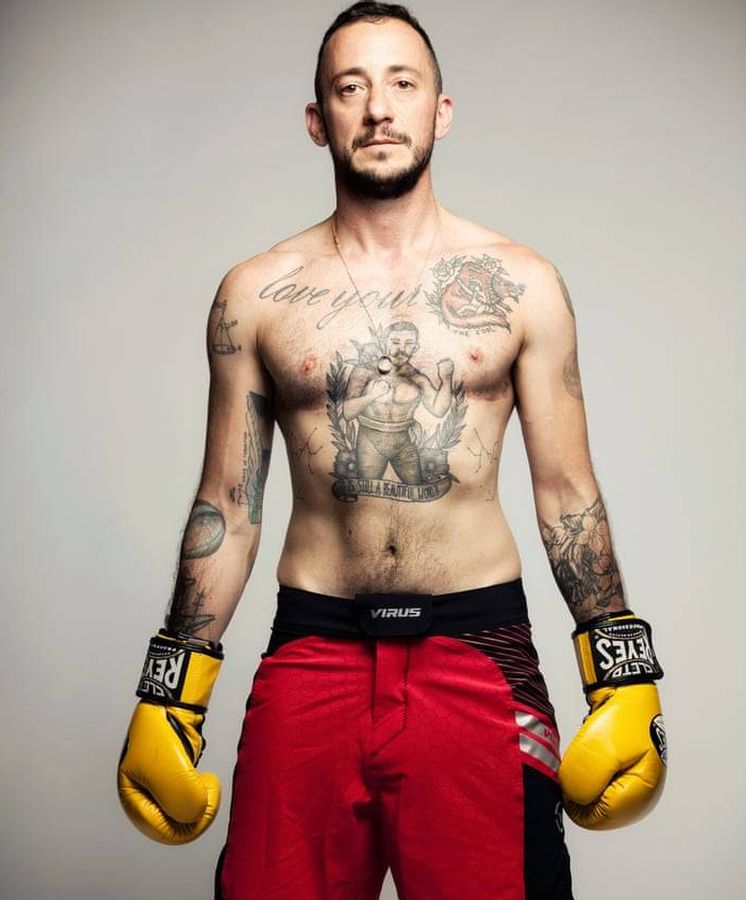 Thomas McBee posando con guantes y pantalón de boxeo, sin camiseta, mostrando tatuajes.