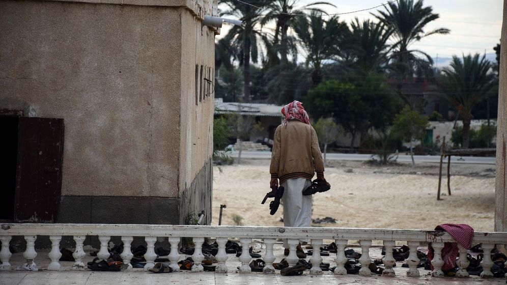 Foto: Un hombre recoge los objetos pertenecientes a las víctimas del atentado de la mezquita Al Rawda, el 25 de noviembre de 2017. (EFE) 