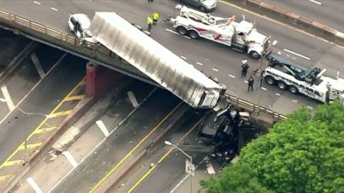 Aparatoso accidente en una autopista de Nueva York: se queda colgando de un puente el tráiler de un camión